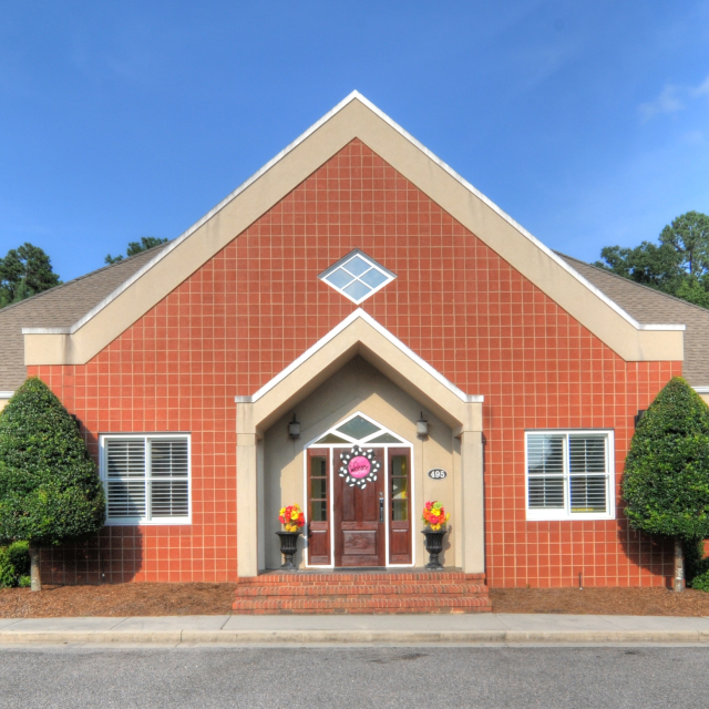Red brick pediatric dental office building with white trim, symmetrical design, and welcoming entrance.